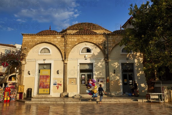 Old town of Nauplion, historic building with round dome and decorated doors, surrounded by trees,