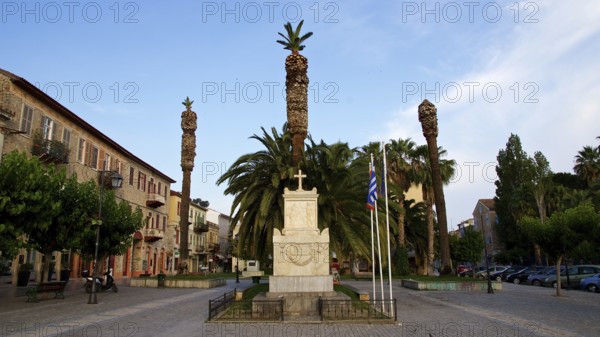 Old town of Nauplion, monument surrounded by palm trees and flags on a cozy town square, Nauplion,