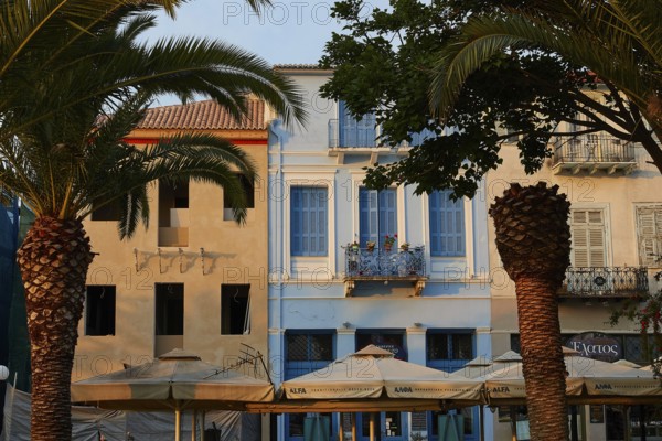Old town of Nauplion, house facades with palm trees and cafés in a Mediterranean evening mood,