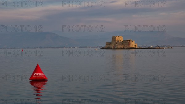 Bourtzi island fortress, historic castle in the evening light on the water with a red buoy,