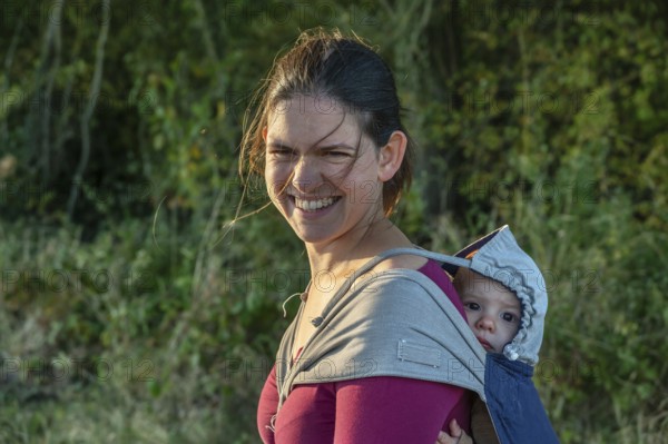 Young mother carrying her baby in a shawl on her back, Othenstorf, Mecklenburg-Western Pomerania,