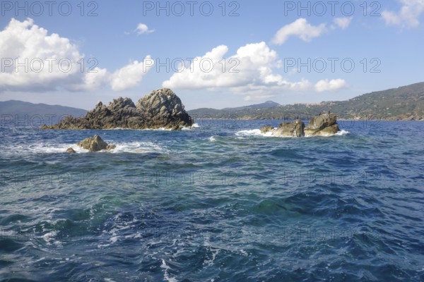 Rock reef with three rocks rising out of the sea Water above water surface Sea level off the coast