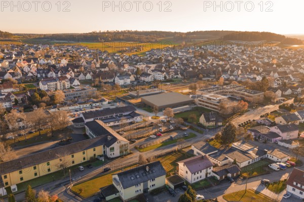 Aerial view of a settlement in warm evening light with hills and landscape in the background,