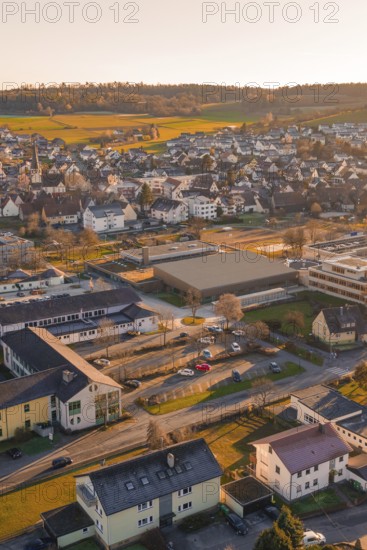 Aerial view of a suburb with buildings and roads in warm sunset light and surrounding hills,