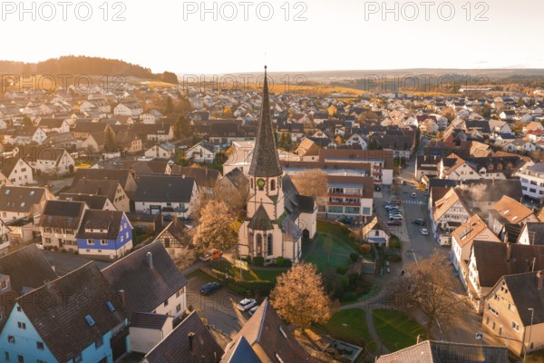 Aerial view of a village with church and autumn trees in soft sunset light, Althengstett, Calw