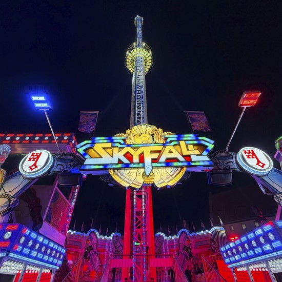 Colourfully illuminated Skyfal free fall tower at night at the All Saints Fair, Soest, North