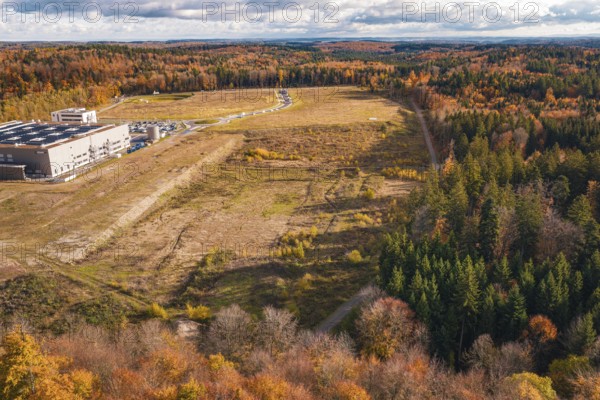 Industrial plant in autumn, surrounded by diverse forest in an open landscape, new Lindenrain