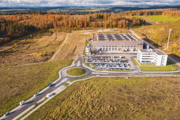 Industrial complex with roundabout, surrounded by forest and empty fields in an autumn environment,