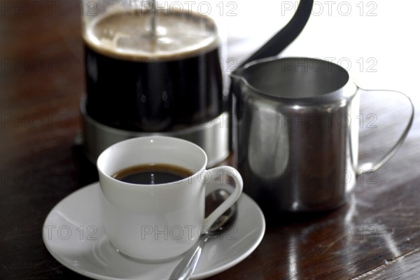 French coffee press next to a cup of coffee and a milk jug on a table, Serenity boutique hotel,