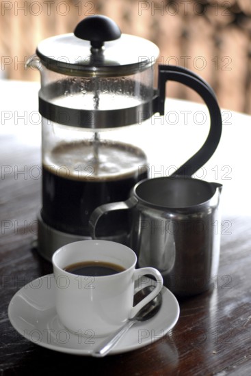 French coffee press next to a cup of coffee and a milk jug on a table, Serenity boutique hotel,