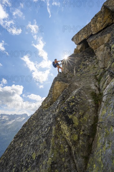 Female mountaineer on steep rock face on the secured via ferrata Krokodil-Bergsee am