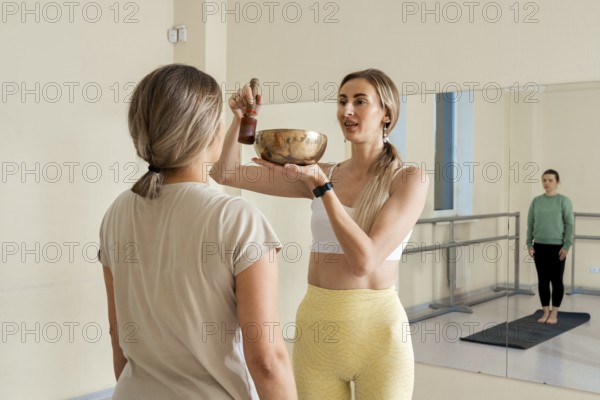 In a peaceful studio, a wellness guide holds a singing bowl while offering a sound therapy session.