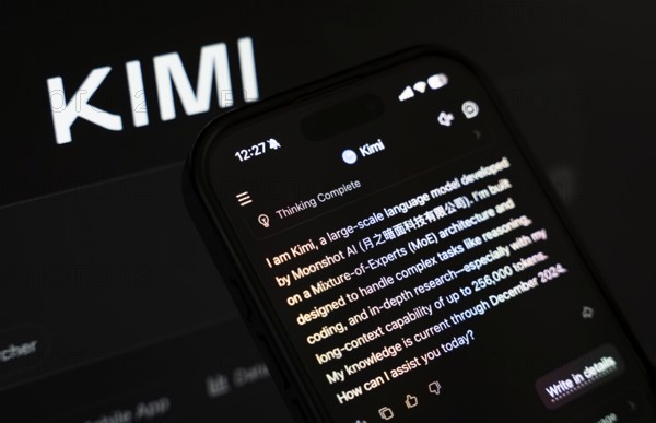 In this photo illustration, a person uses the Kimi AI chatbot on a smartphone while the KIMI logo