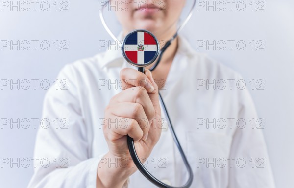Female doctor holding stethoscope with Dominican Republic flag. National health system of Dominican