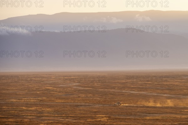 Safari vehicle, Toyota Landcruiser off-road vehicle drives in Ngorongoro Crater at sunrise,
