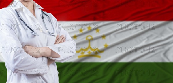 Doctor with crossed arms on Tajikistan flag. Tajikistani health and care concept. Female doctor on