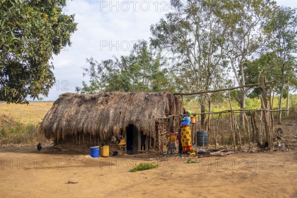 Mother and child in front of a simple traditional clay hut in a Sadaani village, Tanga, Tanzania
