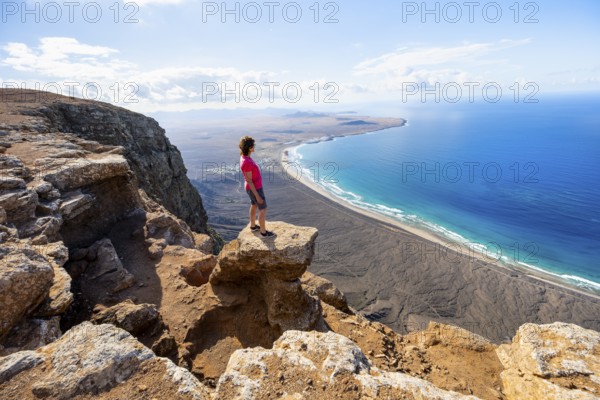 Woman enjoying the view from the Risco de Famara cliffs on Famara beach, Playa de Famara with La