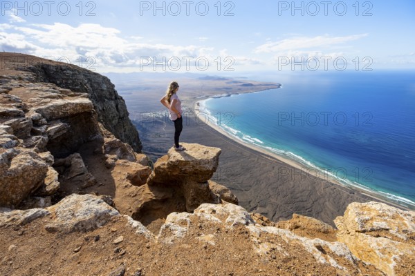 Young woman enjoying the view from the Risco de Famara cliffs to Famara beach, Playa de Famara with