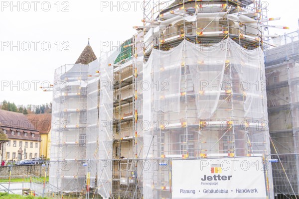 Side of a building with several towers surrounded by large scaffolding for restoration,