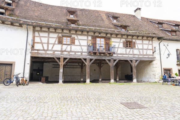 Historic courtyard with half-timbered balcony, paving stones, surrounded by traditional buildings,