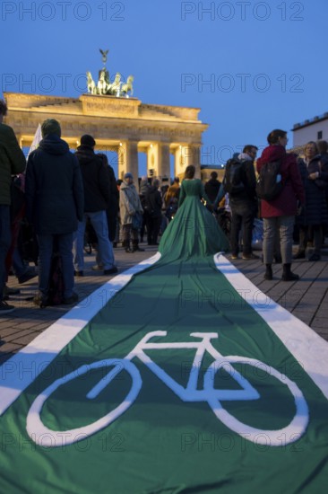 Athena Macke (costume designer) wears a dress with a long train in the shape of a bike path (bike