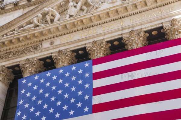 Facade of the New York Stock Exchange, stock exchange with USA national flag on Wall Street,
