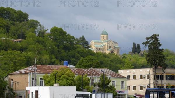 Church on a green hill above city buildings in the foreground, Bagrati Cathedral, Church of the