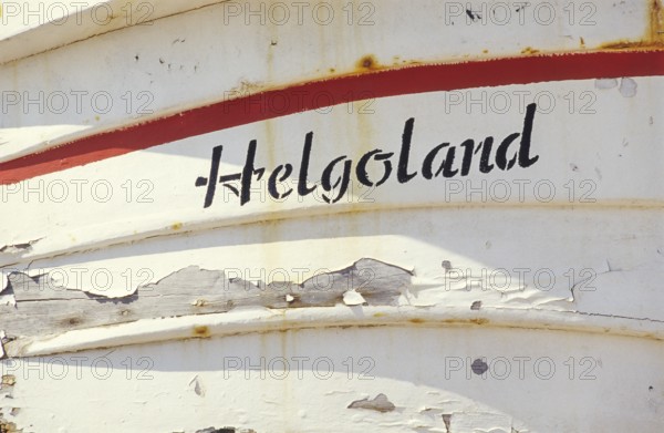 Weathered Heligoland lettering on white boat with red accents on a sunny day, bright, friendly,
