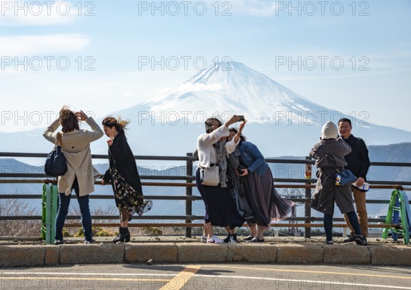 Tourists enjoy the view and take pictures, view of the snow-covered summit of Mount Fuji volcano in