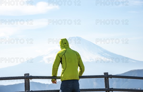 Tourist enjoying the view of the snow-covered summit of Mount Fuji volcano in spring, ÅŒwakudani,