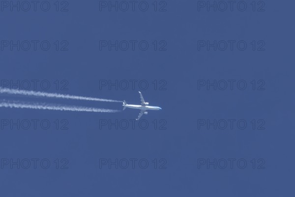 Jet passenger aircraft flying in a blue sky with contrails or vapour trails behind, England, United