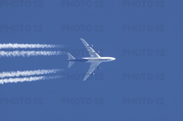 Boeing 747 jumbo jet cargo aircraft of Atlas air airlines flying in a blue sky with contrails or