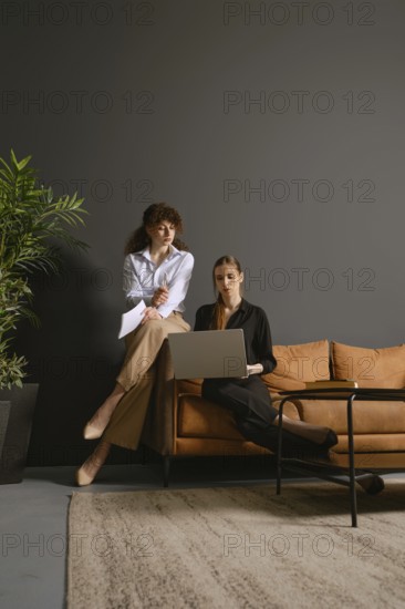 Two women focus on their work as they share ideas and discuss projects while seated in an office