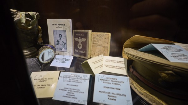 Display case with historical documents and memorabilia, including a book and pictures, workbook,