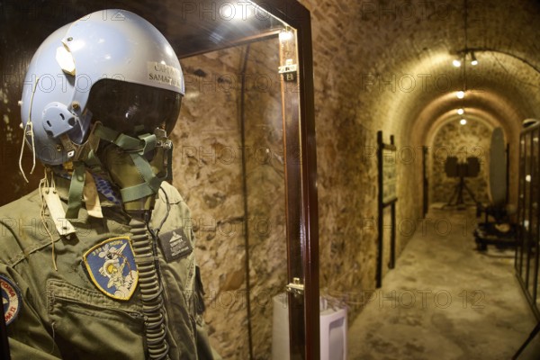 A helmet and pilot's suit behind glass in an illuminated tunnel, War Museum, Military Museum,