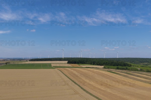 Wide fields with a wind farm on the horizon, under a clear blue sky, near Volkach, aerial view,