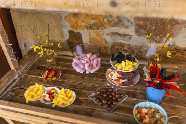 Delicious assortment of colorful candies presented on wooden table at a wedding reception, creating