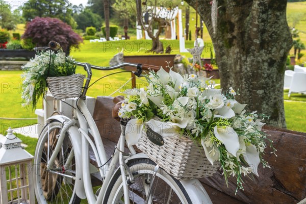 White vintage bicycle with wicker baskets full of white flowers, creating a romantic atmosphere for
