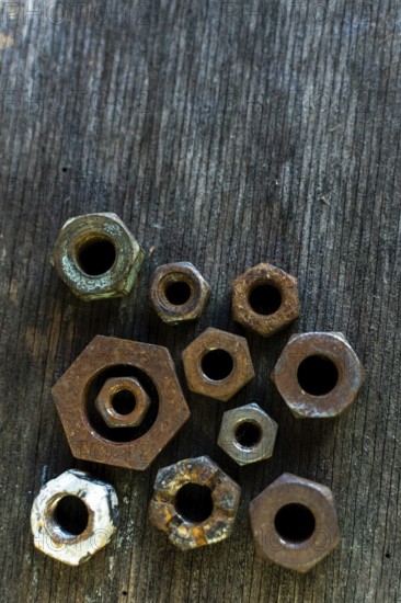 Collection of rusted metal nuts arranged on a weathered wooden surface highlighting unique textures
