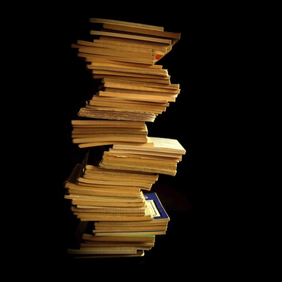 Stack of neatly organized books arranged vertically against a dark backdrop highlighting their