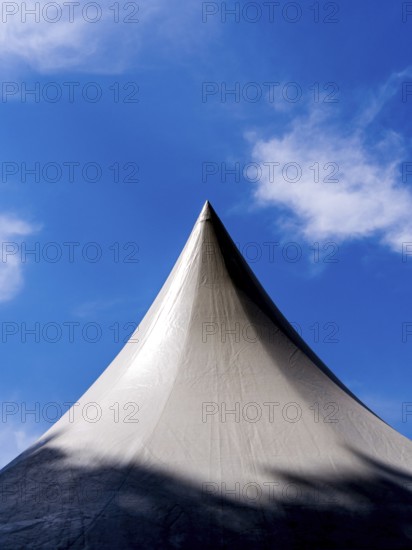 Exhibition tent under a bright blue sky adorned with fluffy clouds in a lively outdoor setting