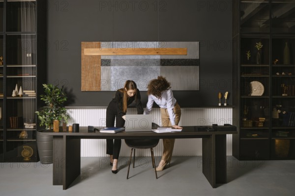 Two business professionals are engaged in a collaborative discussion around a laptop at a sleek