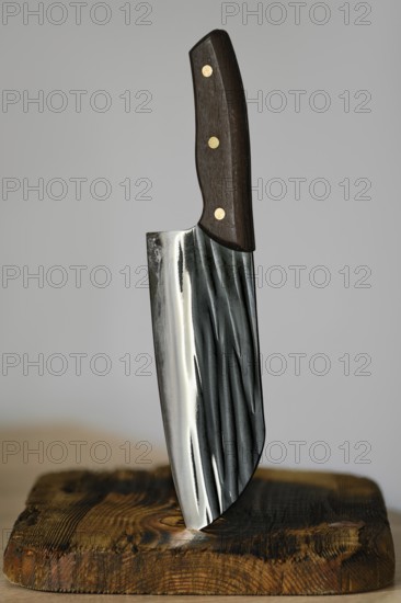 Serbian kitchen knife stuck in a rustic wooden block. The knife features a sleek, shiny blade with