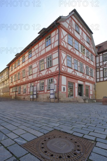 Red Luther House and square manhole cover with town coat of arms, cobblestones, view from below,