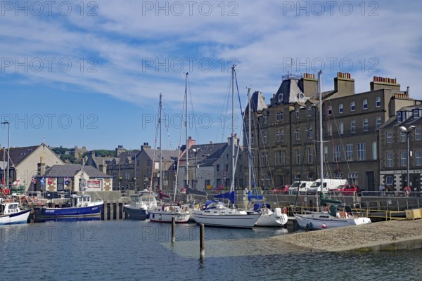Coastal harbour with sailing boats and historic buildings under a bright blue sky, Kirkwall, Orkney