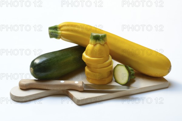 Green and yellow courgettes on a wooden board, Cucurbita pepo