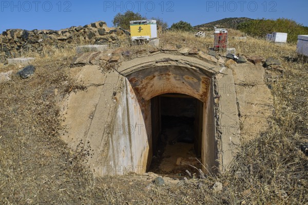 Lost Place, concrete bunker entrance in dry landscape under blue sky with vegetation, Italian air