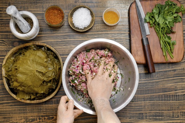 At home, a person mixes seasoned minced meat with rice and herbs in a large bowl. Surrounding the