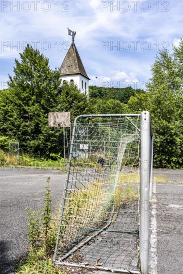Old sports field, with asphalt floor, weeds reclaiming the field, apparently abandoned football
